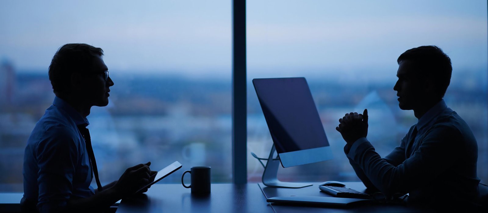 Two professionals discussing strategy in an office at dusk